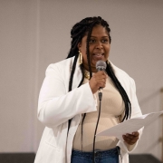 A secretária adjunta da SJCDH, Caroline Moreira, uma mulher negra de tranças pretas e longas, que veste um blazer branco, fala ao microfone.

Autoria da descrição da foto: Wagner Meirelles Ascom SJCDH