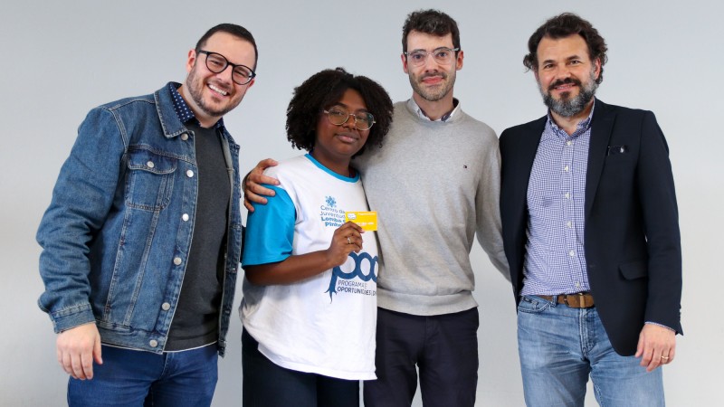 Autoridades posadas ao lado de jovem que recebeu o cartão. Todos sorriem.