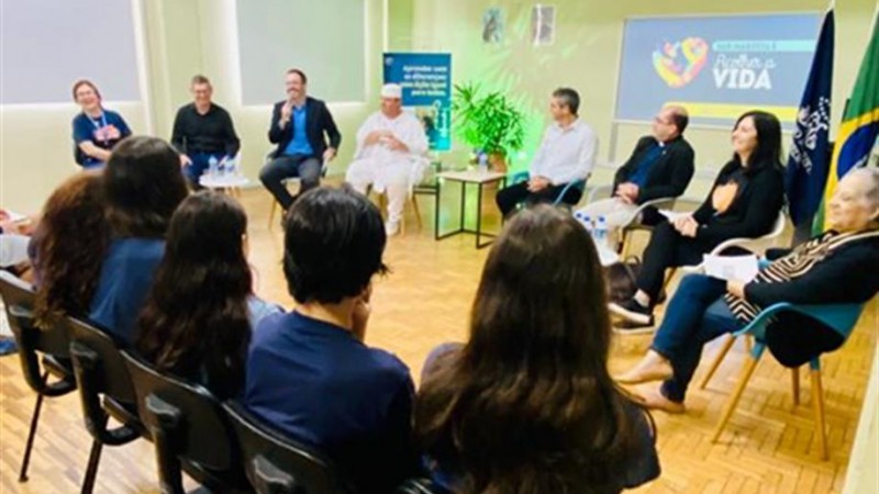 Autoridades religiosas estão em frente ao público apresentando suas tradições.
