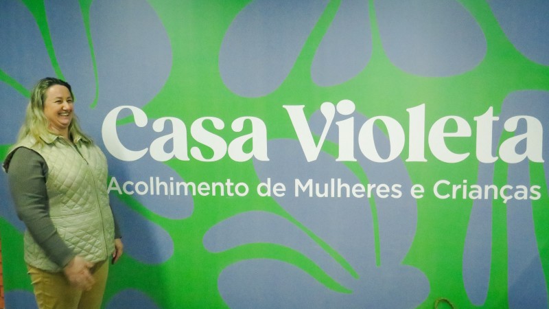Denize em frente a placa da Casa Violeta