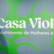 Denize em frente a placa da Casa Violeta 