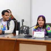 Mulher latina, com faixa na cabeça, e camiseta com as bandeiras do Brasil e da Venezuela.