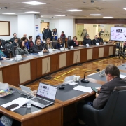 Mesa circular com espaço vazio no meio, com todos os convidados do evento sentados ao redor. 