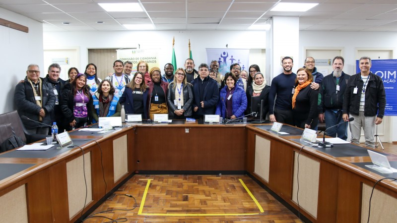 Homens e mulheres atrás da mesa circular do evento, posando para a foto.