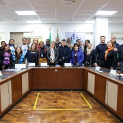 Homens e mulheres atrás da mesa circular do evento, posando para a foto.